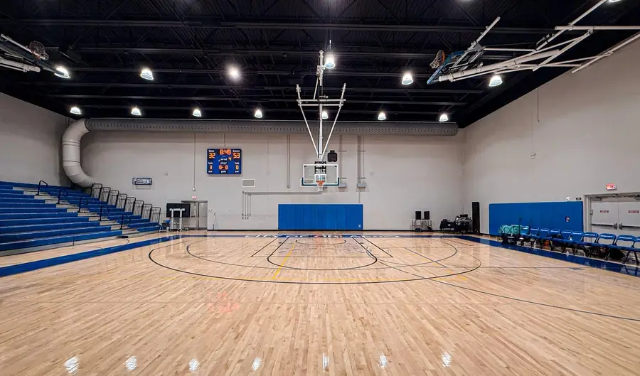 Pavilhão desportivo vazio com piso de madeira e as marcações de andebol pintadas