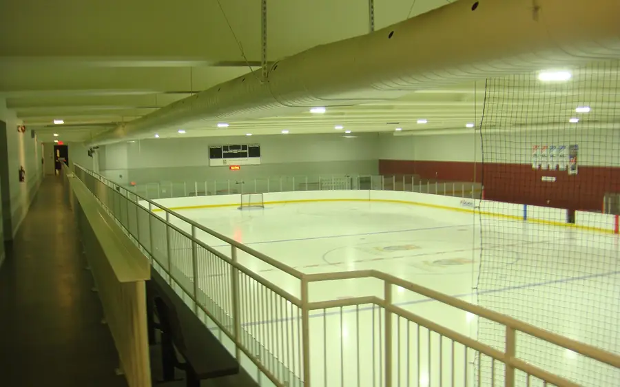 Pista de gelo de um pavilhão comunitário vista da galeria superior, com os bancos junto às tabelas