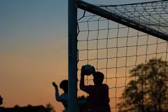 Silhueta de um guarda-redes a agarrar a bola ao fim da tarde, contra um céu claro
