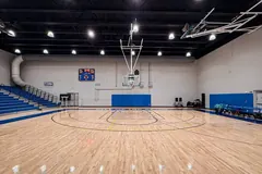 Pavilhão desportivo vazio com piso de madeira e as marcações de andebol pintadas