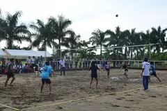 Jogo de voleibol de praia visto à distância, com a rede montada sobre a areia