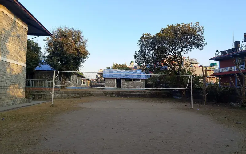 Campo de voleibol de areia junto a um pavilhão, com a rede montada e as linhas delimitadas