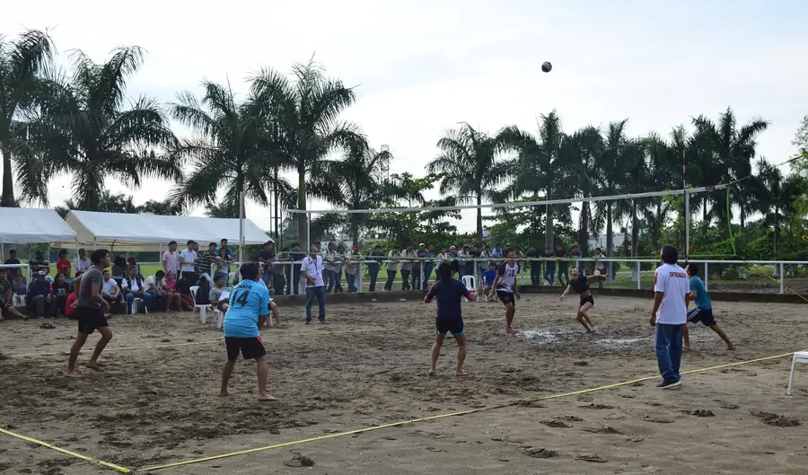 Jogo de voleibol de praia visto à distância, com a rede montada sobre a areia